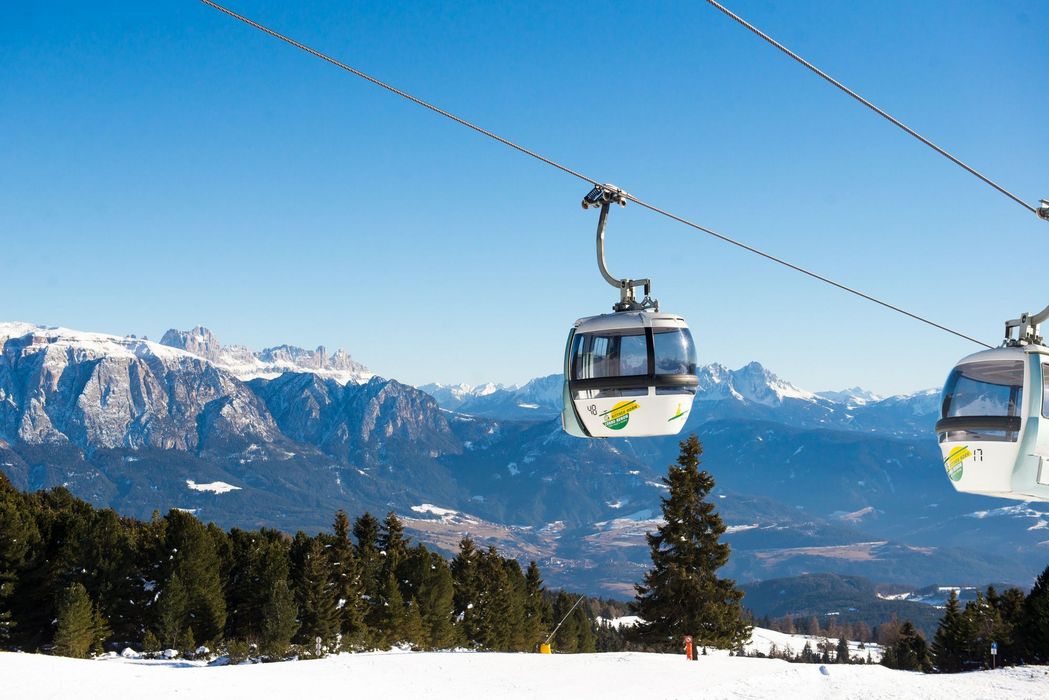 Cabine della funivia con montagne innevate sullo sfondo sotto un cielo azzurro
