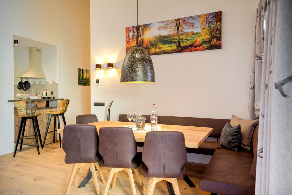 Modern dining area with wooden table, brown chairs, and a large pendant light.