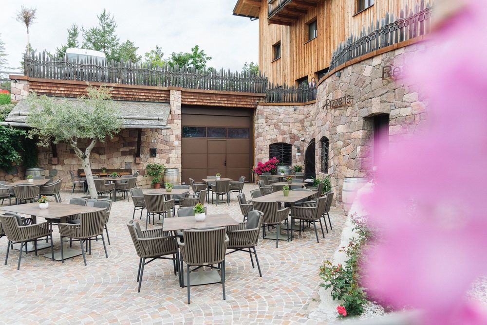 Freiluftterrasse eines Restaurants mit Tischen, Stühlen und Steinmauern