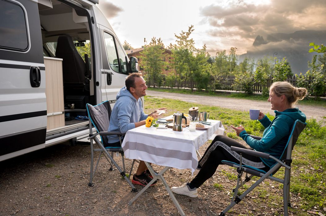 Coppia che fa colazione all'aperto vicino a un camper in una zona verde