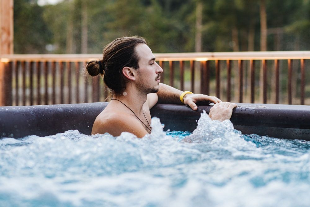 Man relaxing in a hot tub outdoors with bubbling water