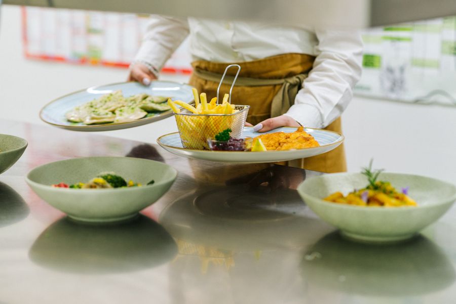 Cameriere che porta piatti di cibo a una tavola in un ristorante.