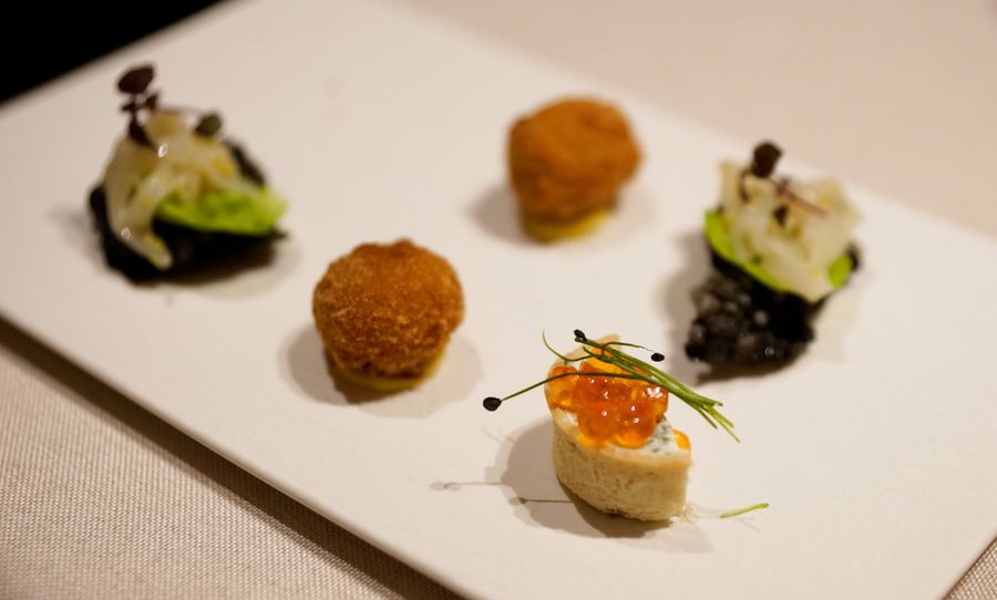 Varie piccole porzioni di antipasti gourmet su un piatto bianco.