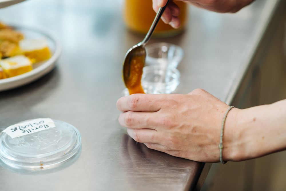 Mano che versa una marmellata da un cucchiaio in un barattolo di vetro su un tavolo inox. Mano che versa una marmellata da un cucchiaio in un barattolo di vetro su un tavolo inox.