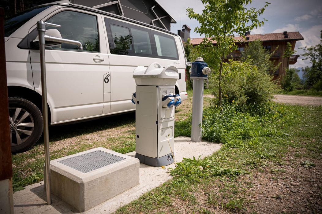 Colonnina di servizio con prese elettriche accanto a un camper bianco in un'area verde