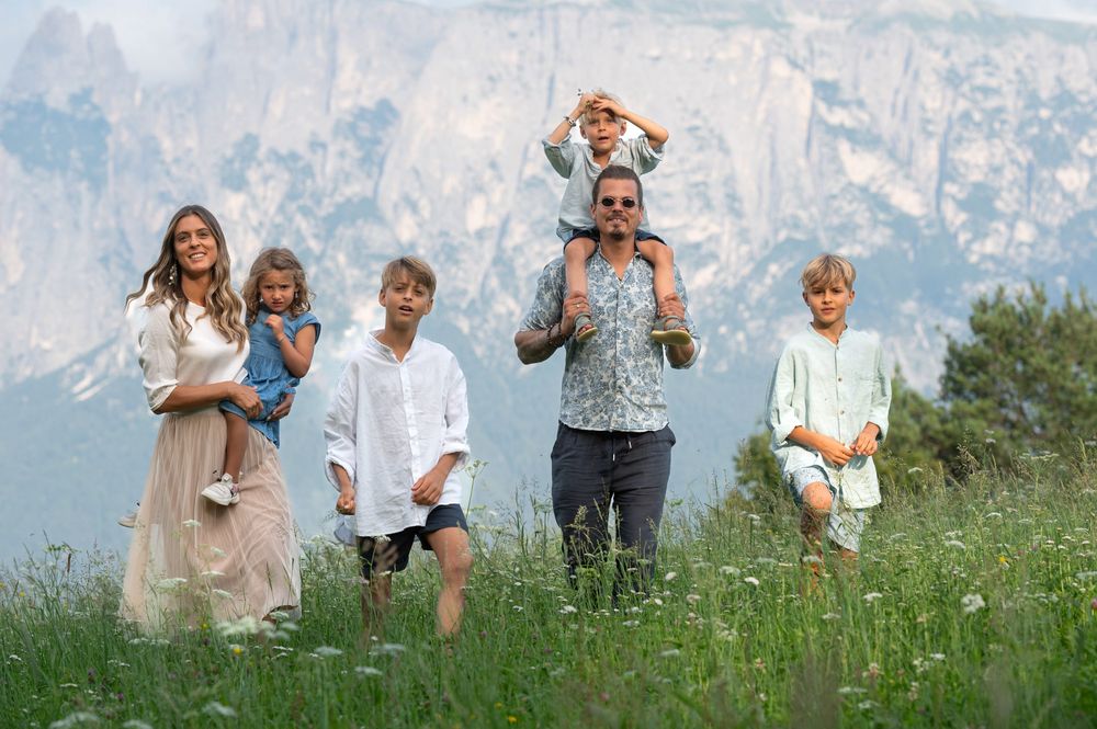 Familie mit vier Kindern in Bergwiese vor Gebirge