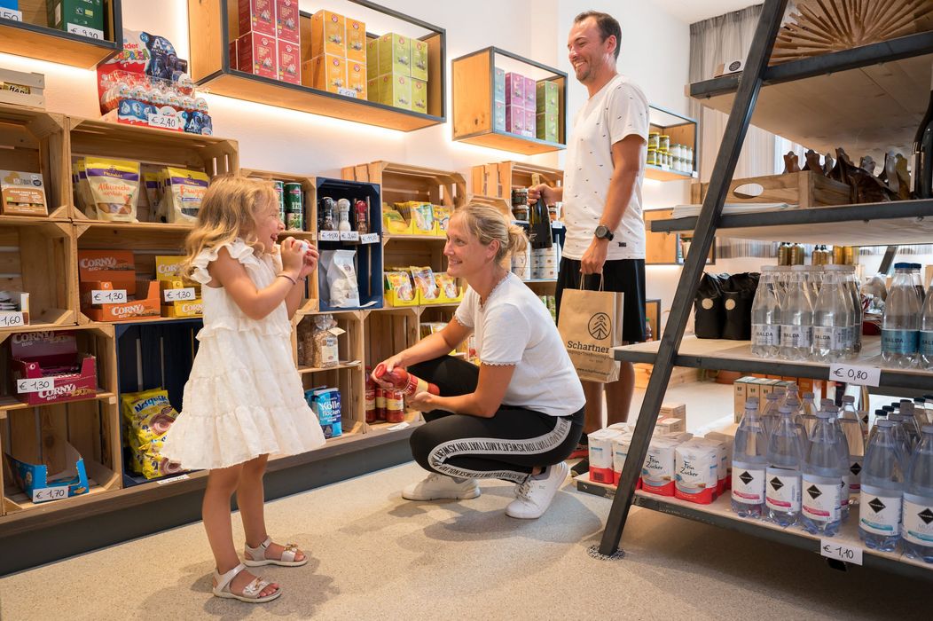 Famiglia che fa la spesa in un negozio alimentare con scaffali di prodotti.