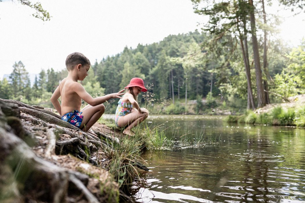 Due bambini che giocano vicino a un lago in un ambiente boschivo