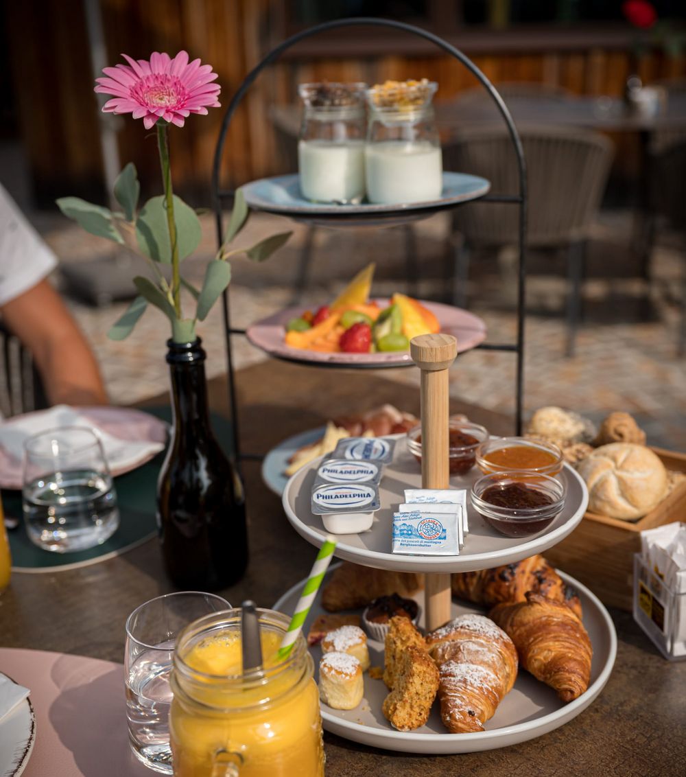 Colazione con vassoio a tre piani, frutta, croissant, marmellate e succo d'arancia su tavolo all'aperto. Colazione con vassoio a tre piani, frutta, croissant, marmellate e succo d'arancia su tavolo all'aperto.