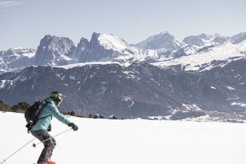 Skifahrer vor schneebedeckten Bergen und klarem Himmel