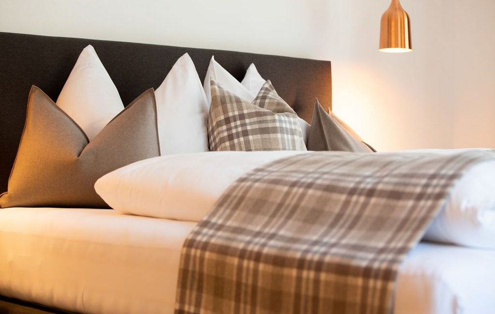 Letto elegante con cuscini bianchi e a quadri e coperta a quadri marroni.