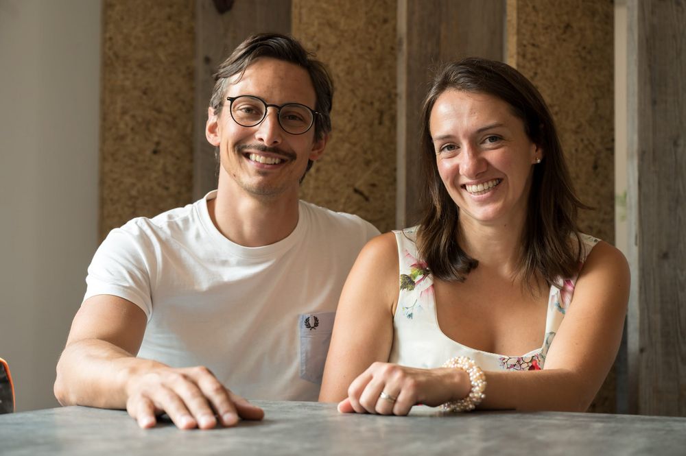 Lächelndes Paar sitzt an einem Tisch vor Holzverkleidung