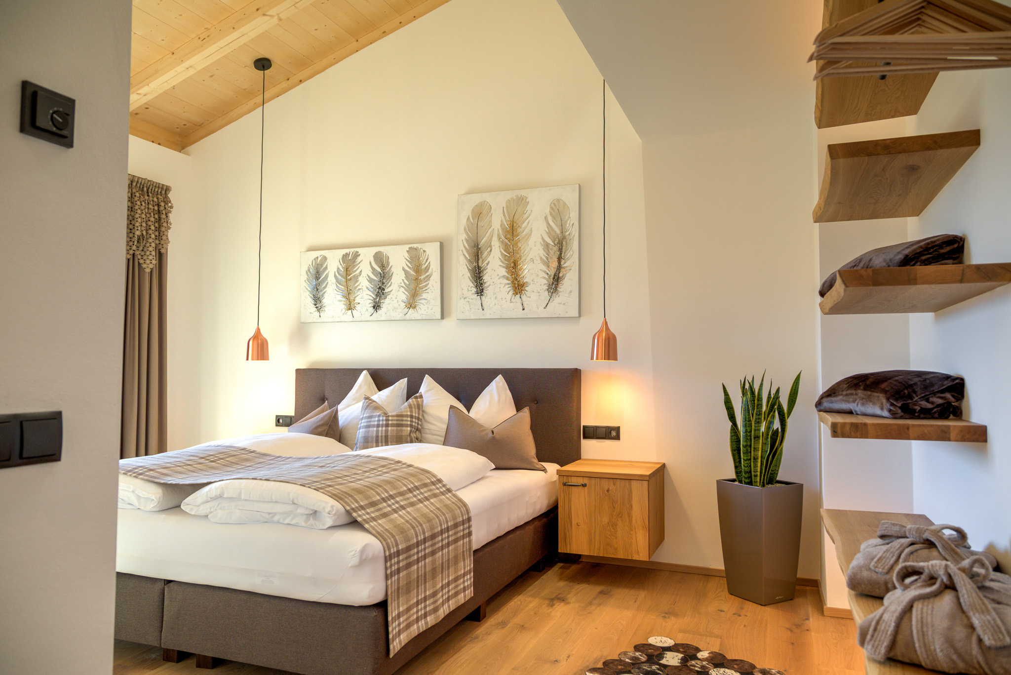 Camera da letto moderna con letto matrimoniale, cuscini, quadri di piume e piante decorative